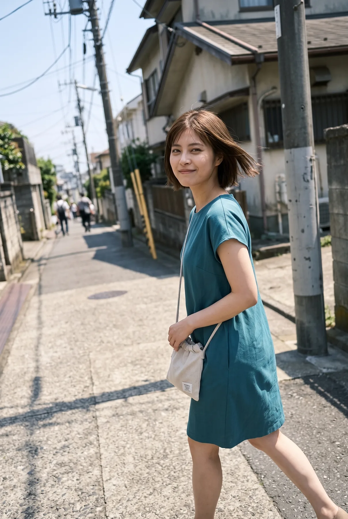 住宅の並ぶ街路で青緑色の半袖ワンピースを着て歩きながら振り向く人物