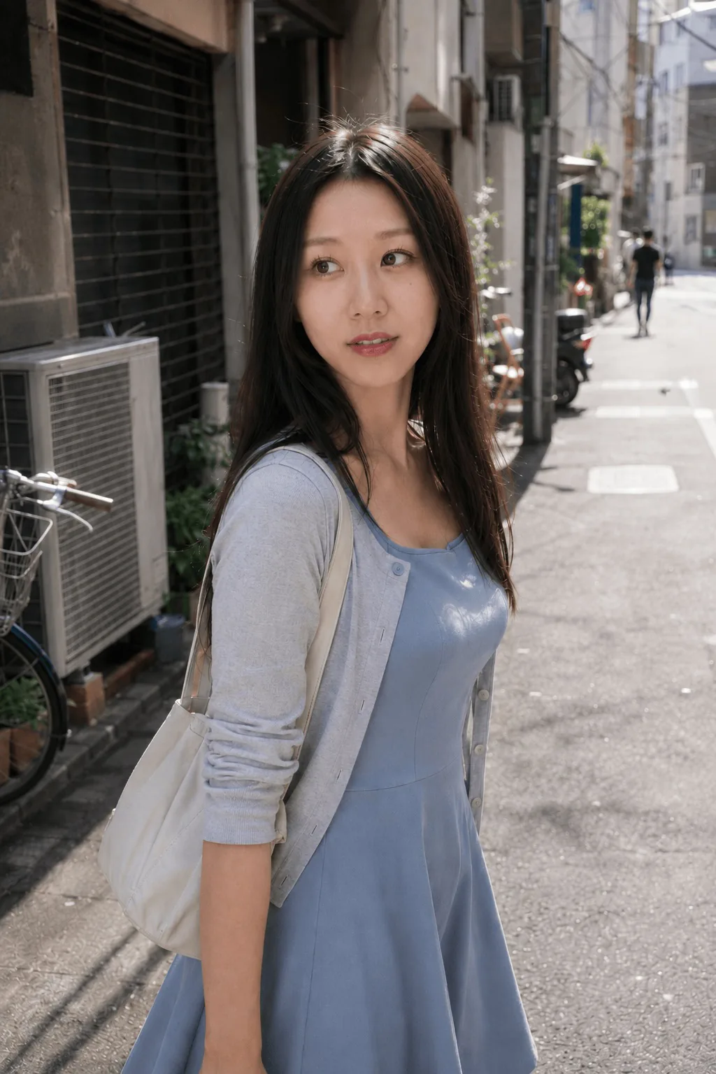 街路で淡い青のワンピースと白いカーディガンを着て正面を見る人物の上半身